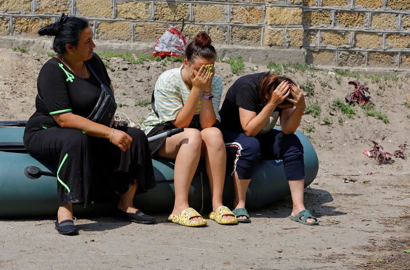 Varias personas se sientan en una barca hinchable tras ser evacuadas de una zona inundada tras el colapso de la presa de Nova Kajovka en el transcurso del conflicto entre Rusia y Ucrania, en la localidad de Hola Prystan, en la región controlada por Rusia de Jersón, Ucrania