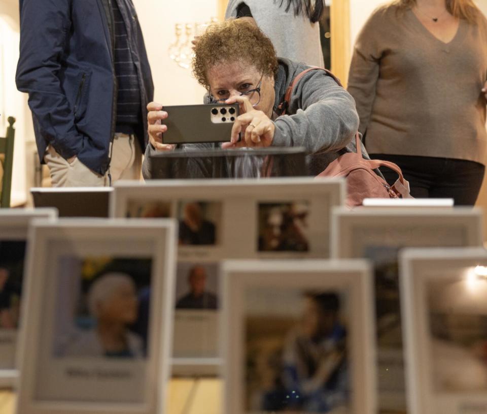 Batya Holin photographs framed pictures of people on display at a home.