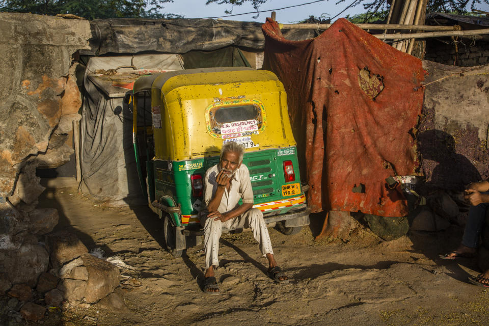 NEW DELHI, INDIA - MARCH 26: An Indian rickshaw driver smokes on the back of his rickshaw as nationwide lockdown continues over the highly contagious novel coronavirus on March 26, 2020 in New Delhi, India. India is under a 21-day lockdown to fight the spread of Covid-19 infections and while the security personnel on the roads are enforcing the restrictions in many cases by using force, the workers of country's unorganized sector are bearing the brunt of the curfew-like situation. According to the international labour organisations India's 90% workforce is employed in the informal sector and most do not have access to pensions, sick leave, paid leave or any kind of insurance. Reports on Thursday said that Prime Minister Narendra Modi's government is preparing a massive bailout to reach to the underprivileged sections of the country and will hand over the dole through direct cash transfers. (Photo by Yawar Nazir/Getty Images)