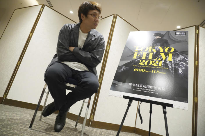 Keisuke Yoshida, a Japanese film director and screenwriter, sits with crossed arms during an exclusive interview with The Associated Press Tuesday, Oct. 5, 2021, in Tokyo. Boxers, janitors, fishermen, the heroes of Yoshida’s movies are Japanese society’s angst-filled losers, struggling in an imperfect world. The director and his three latest works are featured at the Tokyo International Film Festival opening Oct. 30, 2021. (AP Photo/Eugene Hoshiko)