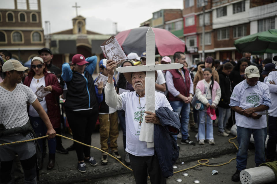 A devotee holds a cross and an image of Jesus Christ during a Good Friday procession in the Ciudad Bolivar neighborhood of Bogota, Colombia, Friday, April 7, 2023. Holy Week commemorates the last week of the earthly life of Jesus culminating in his crucifixion on Good Friday and his resurrection on Easter Sunday. (AP Photo/Ivan Valencia)
