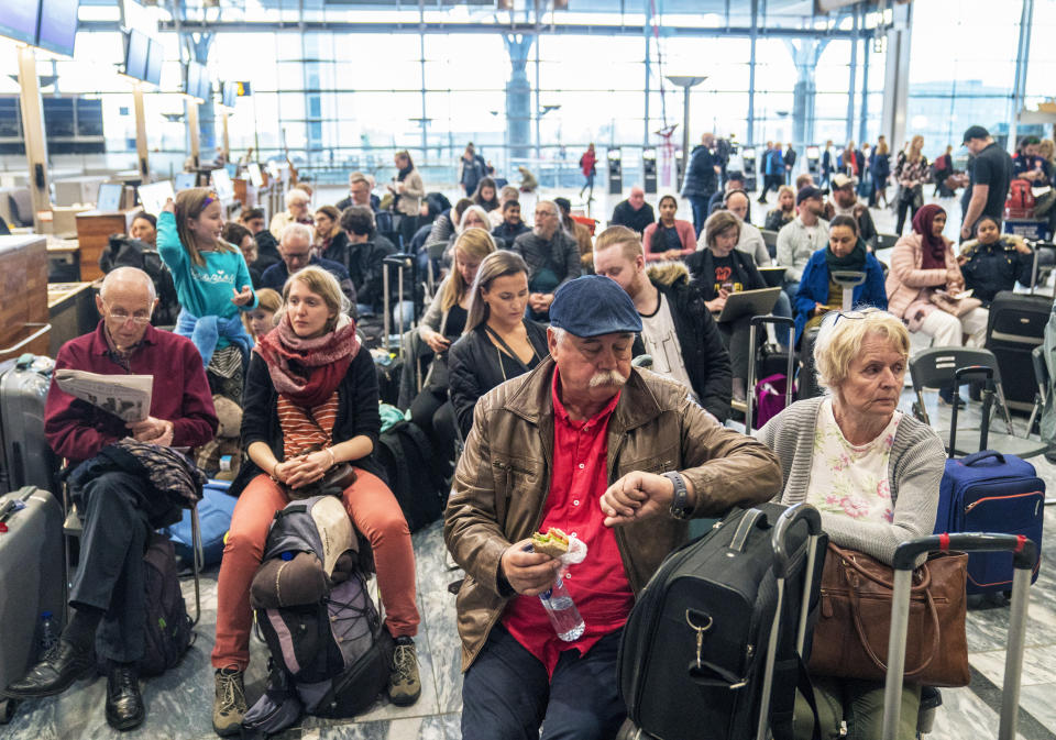 People are seated after flights were cancelled by Scandinavian Airlines, at Oslo Airport in Gardermoen, Norway, Friday, April 26, 2019. Pilots for Scandinavian Airlines have launched an open-ended strike following the collapse of pay negotiations, forcing the company to cancel almost all its flights. (Ole Berg-Rusten/NTB Scanpix via AP)