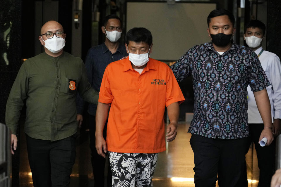 Immigration officers escort Mitsuhiro Taniguchi, 47, of Japan, center, before a press conference at immigration office in Jakarta, Indonesia Wednesday, June 8, 2022. Authorities on the southern tip of Indonesia's Sumatra island arrested a Japanese fugitive accused of fraud in Japan in connection with the receipt of a massive amount of COVID-19 subsidies for small businesses in distress, police said Wednesday.(AP Photo/Achmad Ibrahim)