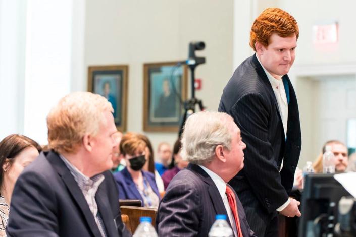 Buster Murdo (right), son of Alex Murdo, walks to the witness stand as his father (left) watches the trial at the Colleton County Courthouse in Walterboro, South Carolina, Tuesday, February 21, 2023.  The 54-year-old veteran lawyer stands trial on two counts of murdering his wife and son at their home and hunting lodge in Colleton County, South Carolina, June 7, 2021.  (Jeff Blake/State via AP, Poole)