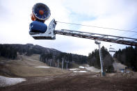 A snow cannon is seen on a ski track with only a few patches of snow on Bjelasnica mountain near Sarajevo, Bosnia, Wednesday, Jan. 4, 2023. (AP Photo/Armin Durgut)