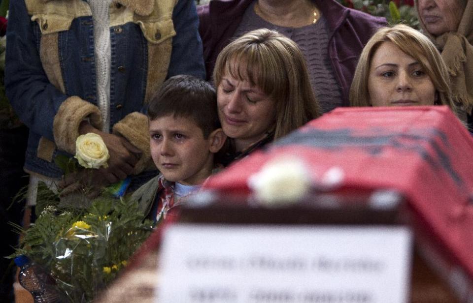 Relatives weep in front of 27 coffins draped with Albanian flag containing the remains of ethnic Albanians killed during 1998-99 Kosovo war in the town of Suva Reka during the funeral ceremony on Wednesday, March 26, 2014. The victims were killed in two separate rampages by Serbs forces in town of Suva Reka and Mala Krusa just days after NATO began a bombing campaign to end an onslaught by Serbia on separatist ethnic Albanians. (AP Photo/Visar Kryeziu)