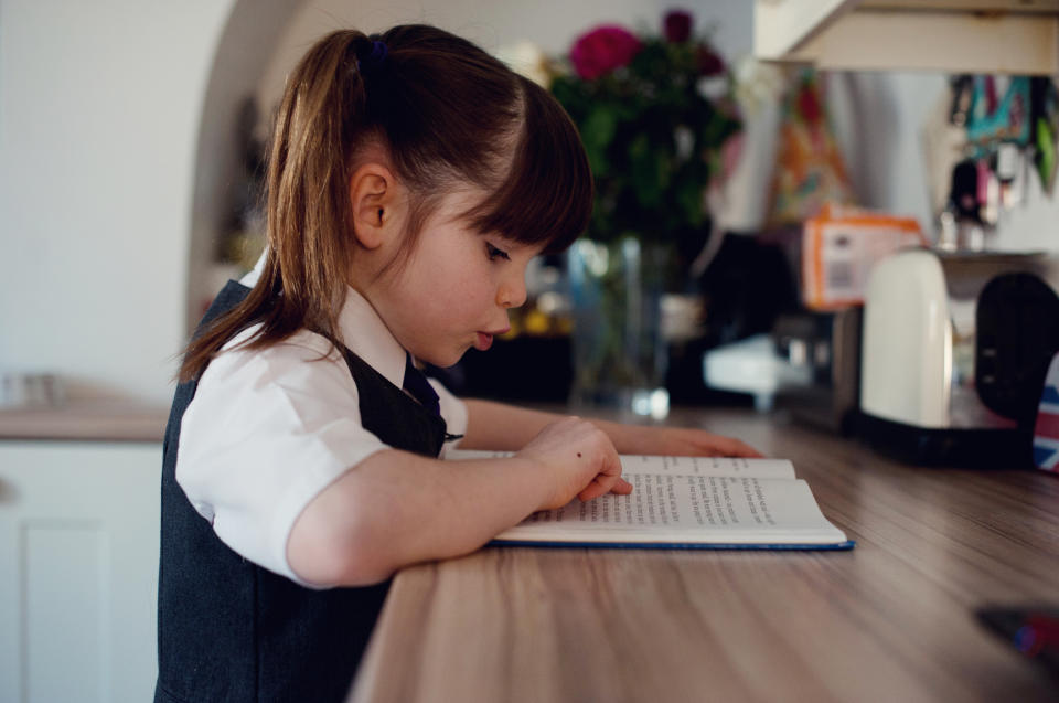 Little girl reading her book and sounding out the words.