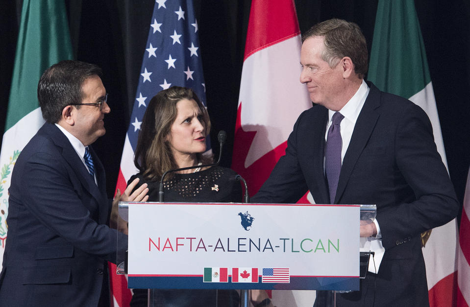 FILE- In this Jan. 29, 2018, file photo foreign Canadian Affairs Minister Chrystia Freeland, center, talks with United States Trade Representative Robert Lighthizer, right, and Mexico's Secretary of Economy Ildefonso Guajardo Villarreal after delivering statements to the media during the sixth round of negotiations for a new North American Free Trade Agreement in Montreal. The new United States-Mexico-Canada Agreement replaces the 24-year-old North American Free Trade Agreement, which tore down trade barriers between the three countries. But NAFTA encouraged factories to move to Mexico to take advantage of low-wage labor in what President Donald Trump called a job-killing “disaster’’ for the United States. (Graham Hughes/The Canadian Press via AP, File)