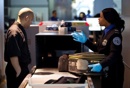 FILE PHOTO - A Transportation Security Administration (TSA) security agent takes a traveler's luggage for a second security check at John F. Kennedy Airport in New York, U.S. on February, 29, 2012. REUTERS/Andrew Burton/File Photo