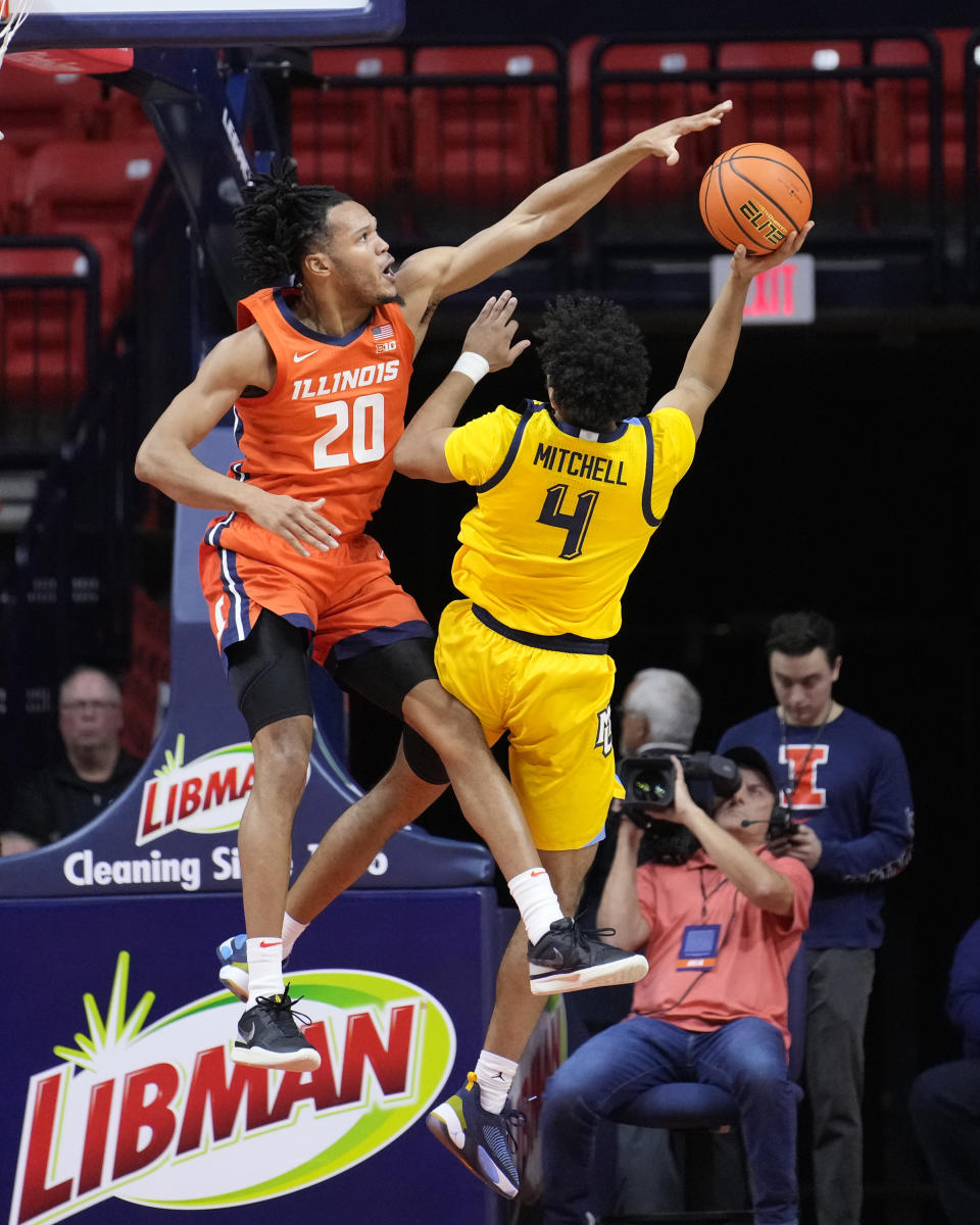 Illinois' Ty Rodgers (20) blocks the shot of Marquette's Stevie Mitchell during the first half of an NCAA college basketball game Tuesday, Nov. 14, 2023, in Champaign, Ill. (AP Photo/Charles Rex Arbogast)