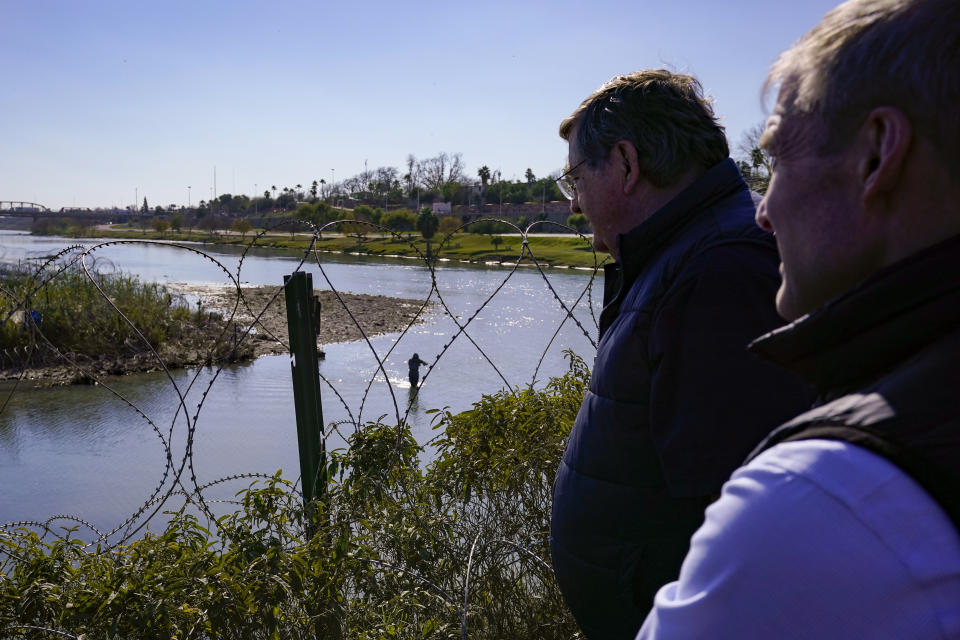 Republican members of Congress look on as migrants cross the Rio Grande at the Texas-Mexico border, Wednesday, Jan. 3, 2024, in Eagle Pass, Texas. U.S. House Speaker Mike Johnson is leading about 60 fellow Republicans in Congress on a visit to the Mexican border. Their trip comes as they are demanding hard-line immigration policies in exchange for backing President Joe Biden's emergency wartime funding request for Ukraine. (AP Photo/Eric Gay)