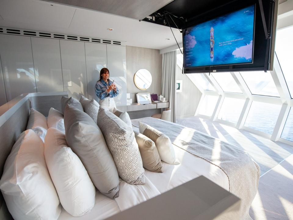 a large bed in front of a TV and a panoramic view of the ocean