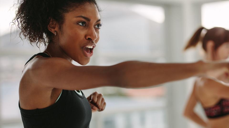 African young woman doing intense punching work out at the gym.