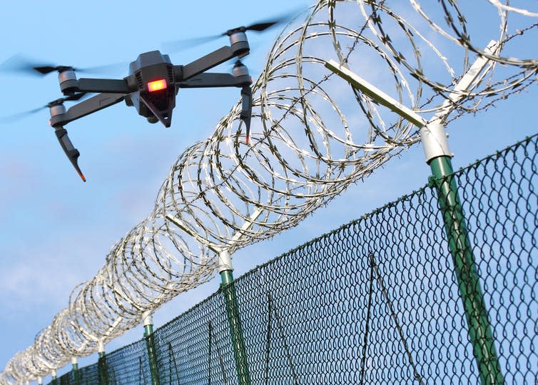 <span class="caption">Watchful security guard, or motorised drug mule?</span> <span class="attribution"><a class="link " href="https://www.shutterstock.com/image-photo/drone-monitoring-barbed-wire-fence-on-790134829?src=IOwbjTikLPcWJjA4yBr7lQ-1-75" rel="nofollow noopener" target="_blank" data-ylk="slk:shutterstock;elm:context_link;itc:0;sec:content-canvas">shutterstock</a></span>