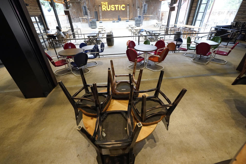 Chairs are stacked on a table inside The Rustic, Friday, June 26, 2020, in Houston. The restaurant and bar will be limited to 50% capacity after Texas Gov. Greg Abbott announced Friday that he is shutting bars back down and scaling back restaurant capacity to 50%, in response to the increasing number of COVID-19 cases in Texas. (AP Photo/David J. Phillip)