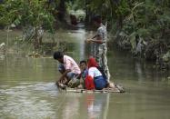 Villager uses a raft to move across a flooded locality in a flood effected village in Morigaon district of Assam in India on Friday, 17 July 2020. (Photo by David Talukdar/NurPhoto via Getty Images)