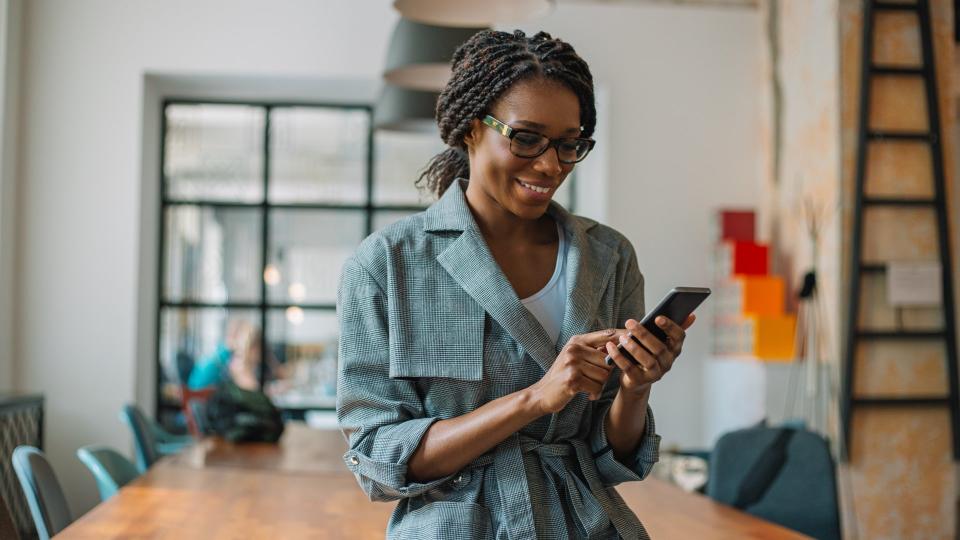 Black businesswoman using smart phone while sitting on desk in New modern Office.