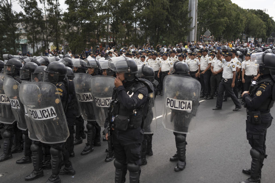 Police in riot gear stand on a highway blocked by demonstrators during a national strike, in Guatemala City, Tuesday, Oct. 10, 2023. People are protesting to support President-elect Bernardo Arévalo after Guatemala's highest court upheld a move by prosecutors to suspend his political party over alleged voter registration fraud. (AP Photo/Santiago Billy)