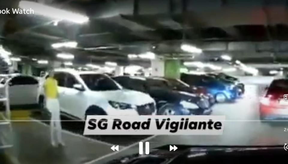 A woman in Singapore failed to reserve a parking lot for her husband after a driver reversed their vehicle into the lot the woman was standing on. — Screen capture via  Facebook/ SG Road Vigilante