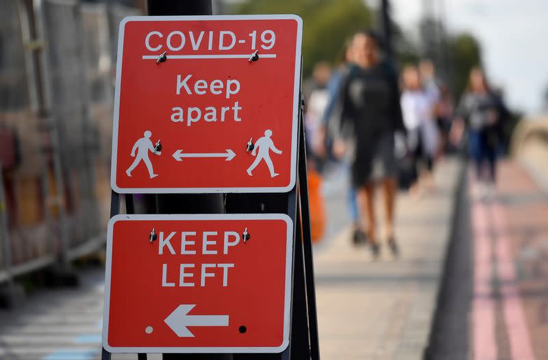 FOTO DE ARCHIVO: Peatones caminan cerca de las pancartas con avisos de salud pública en Londres, Reino Unido, el 11 de septiembre de 2020