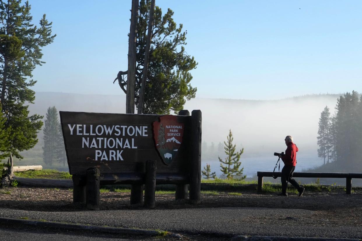 A man takes a picture at the south entrance of Yellowstone National Park, as he waits to gain entry for the first time in more than a week, on June 22, 2022 in Yellowstone National Park, Wyoming
