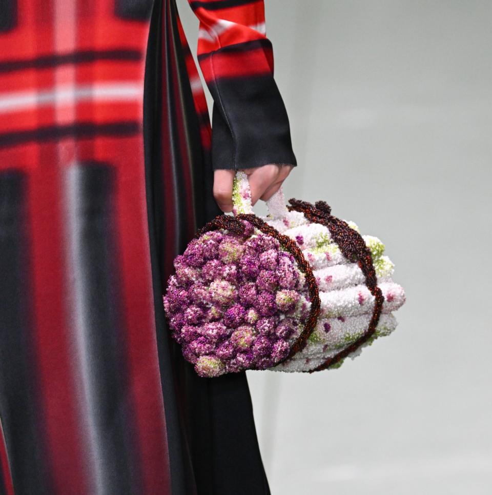 Woman carrying a bag that looks like a bundle of asparagus