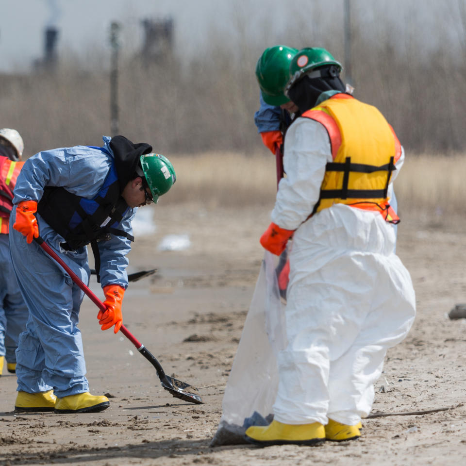 In this March 25, 2014 photo, a worker combs the beach in Whiting, Ind. Crews for oil giant BP worked Tuesday to clean up an undetermined amount of crude oil that spilled into Lake Michigan and affected about a half-mile section of shoreline near Chicago following a malfunction at BP's northwestern Indiana refinery, officials said. (AP Photo/Sun-Times Media, Jim Karczewski) MANDATORY CREDIT, MAGS OUT, NO SALES