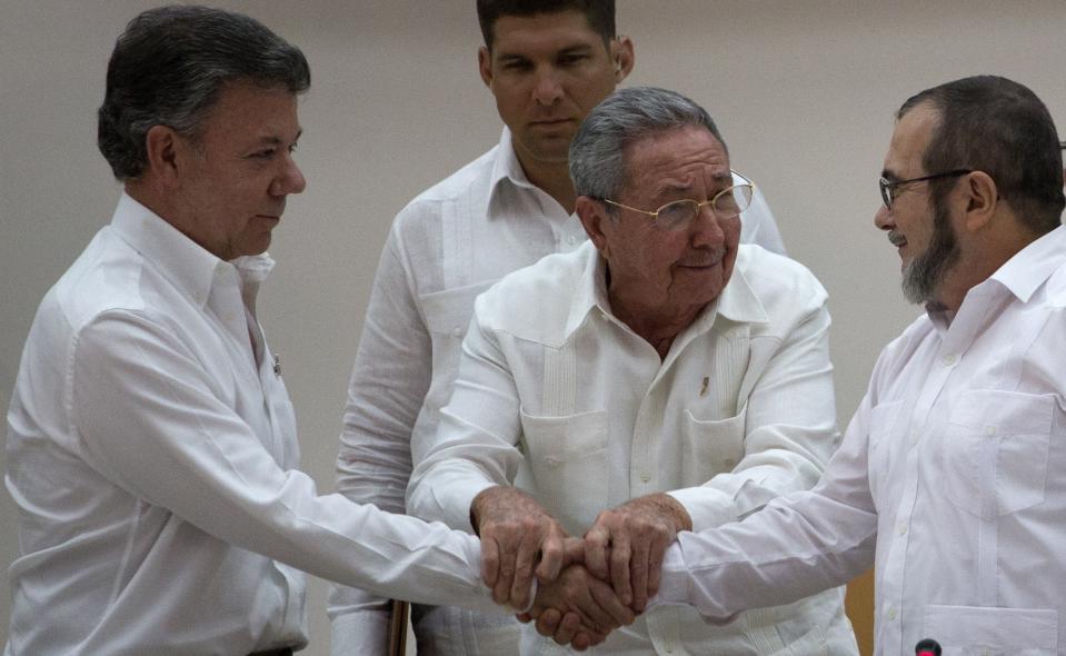 FILE - In this Sept. 23, 2015 file photo, Cuba's President Raul Castro brings together the hands of Colombian President Juan Manuel Santos, left, and Commander the Revolutionary Armed Forces of Colombia FARC) Timoleon Jimenez during a ceremony in Havana, Cuba, after Santos and the FARC overcame the last significant obstacle to a peace deal. (AP Photo/Desmond Boylan, File)