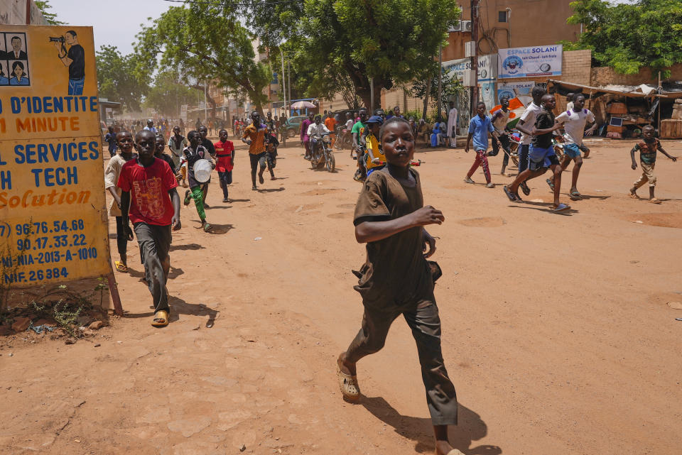 Children run in the streets of Niamey, Niger, Sunday, Aug. 13, 2023. People marched, biked and drove through downtown Niamey, chanting "down with France" and expressing anger at ECOWAS. (AP Photo/Sam Mednick)