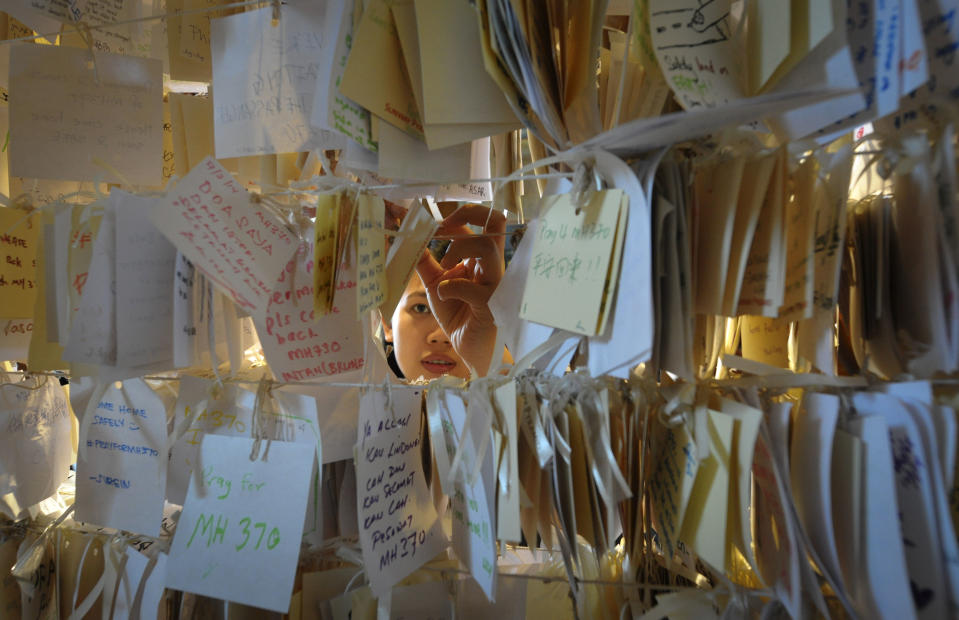 A woman ties a message card for passengers onboard the missing Malaysia Airlines Flight 370 at a shopping mall in Petaling Jaya, near Kuala Lumpur, Malaysia, Thursday, April 10, 2014. With hopes high that search crews are zeroing in on the missing Malaysian jetliner's crash site, ships and planes hunting for the aircraft intensified their efforts Thursday after equipment picked up sounds consistent with a plane's black box in the deep waters of the Indian Ocean. (AP Photo)