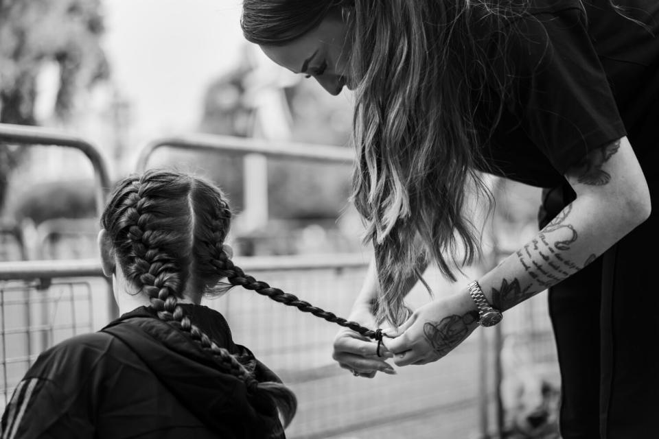 To pass the time, hair is braided as members of the public pass the time camping out along the route