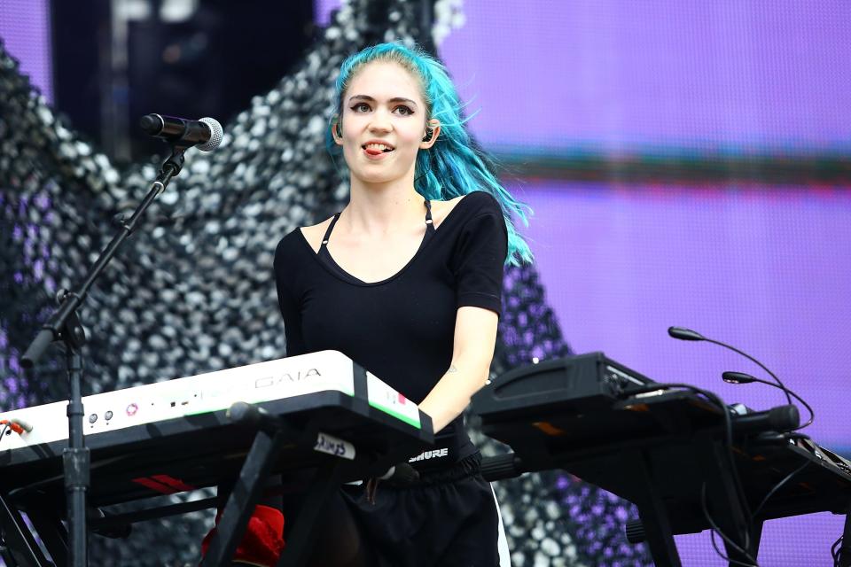 Grimes plays keyboard on a stage