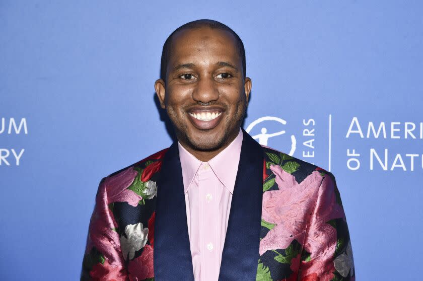 A man smiling in a floral suit against a blue background