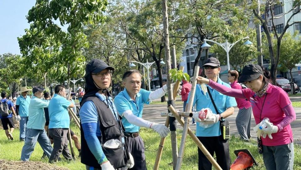 屏東市千禧公園茄冬樹遭強風摧殘傾斜，多個民間團體自發護樹，協助公所救災。（記者毛莉攝）