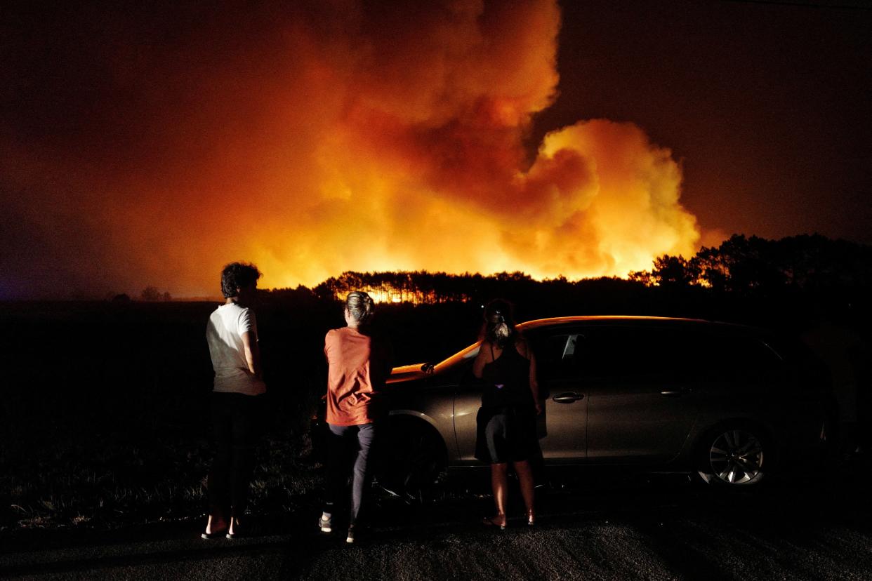 People watch a wildfire in Aljezur, Portugal, 7 August (REUTERS)