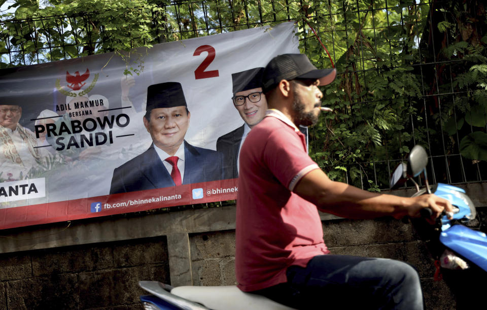 A man rides his motorcycle past a campaign banner for Indonesian presidential candidate Prabowo Subianto, left, and his running mate Sandiaga Uno, in Jakarta, Indonesia, Thursday, Jan. 17, 2019. Echoing the campaign tactics of Donald Trump, former Indonesian Gen. Subianto says his country, the world's third-largest democracy, is in dire shape and he is the leader who will restore it to greatness. (AP Photo/Dita Alangkara)