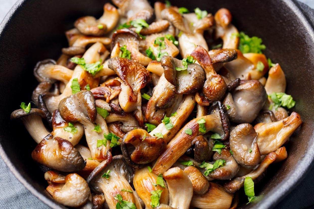 fried mushrooms with fresh herbs in black cast iron pan