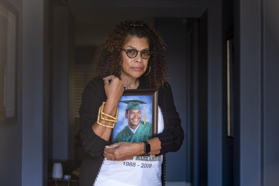 A woman holds a graduation photo of her son