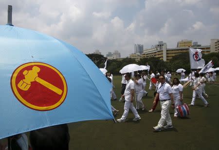 People's Action Party (PAP) supporters pass a Workers' Party supporter (L) carrying an umbrella at a nomination center ahead of the general elections in Singapore September 1, 2015. REUTERS/Edgar Su