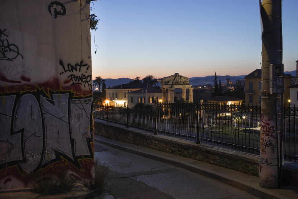 In this Sunday, July. 7, 2019 photo, the facade of a building and an electricity pole are covered with graffiti in front the Gate of the ancient Roman agora in Plaka district of Athens. Some parts of central Athens are so afflicted with graffiti _ largely undecipherable squiggles in bold, broad strokes _ that few facades remain untouched and property owners give up on repainting. (AP Photo/Petros Giannakouris)