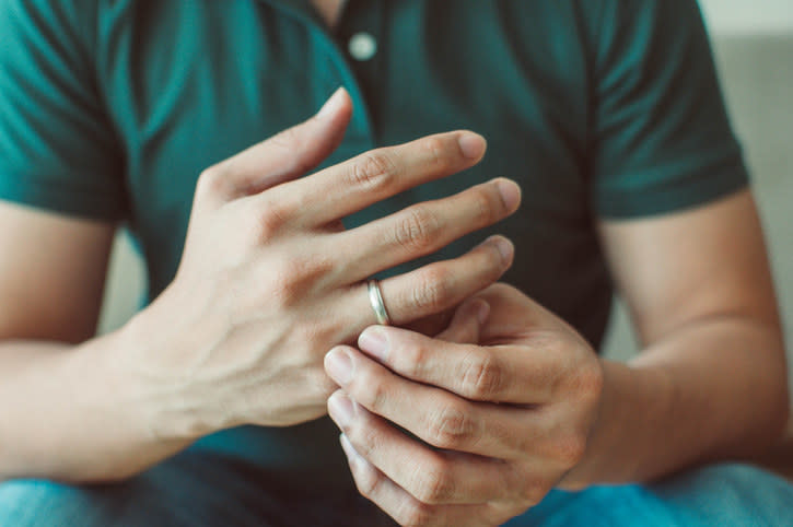 close up of hands touching a wedding ring on the finger