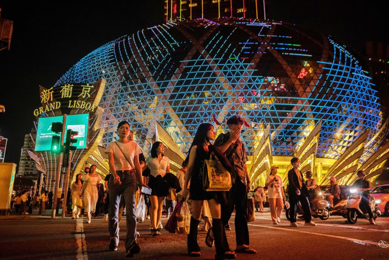 Visitors cross the street in front of the Grand Lisboa casino resort, operated by SJM Holdings Ltd., during Golden Week at night in Macau, China, on Sunday, April 30, 2023. Photographer: Eduardo Leal/Bloomberg