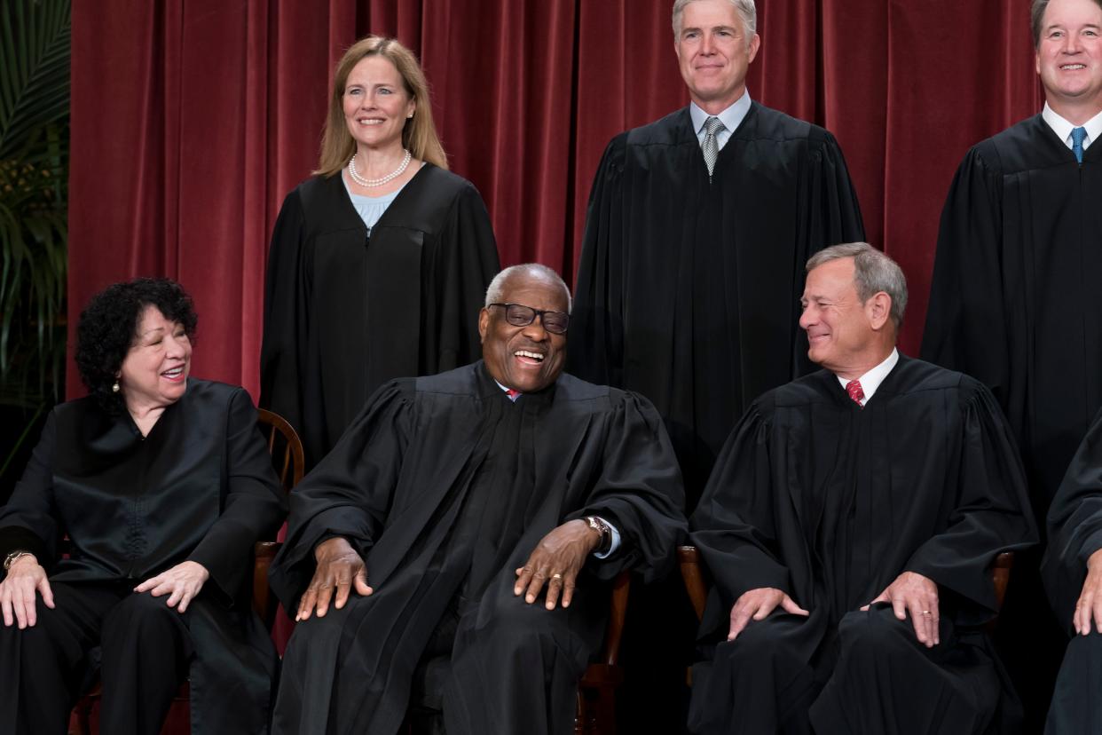 Justice Clarence Thomas laughs as members of the Supreme Court pose for a portrait