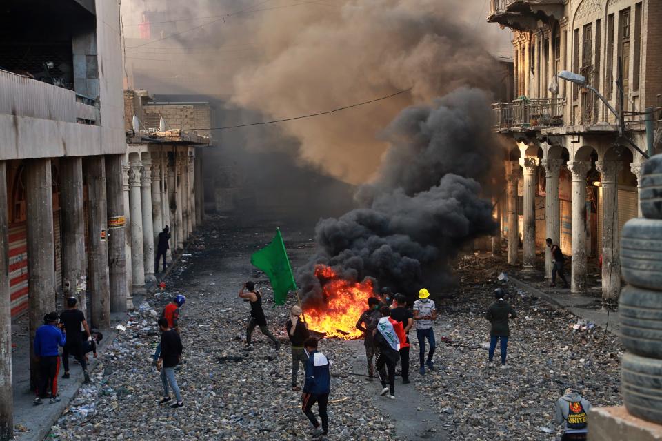 FILE - In this Nov. 28, 2019 file photo, anti-government protesters set fire while security forces close Rasheed Street during clashes in Baghdad, Iraq. As the Middle East ushers in 2020, a new kind of uprising is unfolding in the Arab world. While the 2011 Arab Spring uprisings that took place in Egypt, Tunisia, Libya and Syria were directed at long-ruling autocrats, the current economically driven uprisings are directed at corrupt political elites who have failed at providing their people with basic services. (AP Photo/Khalid Mohammed, File)