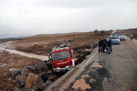 Firefighters look at a destroyed firefighter truck on a road where a firefighter died as heavy rain and flash floods hit Campillos, southern Spain, October 21, 2018. REUTERS/Jon Nazca