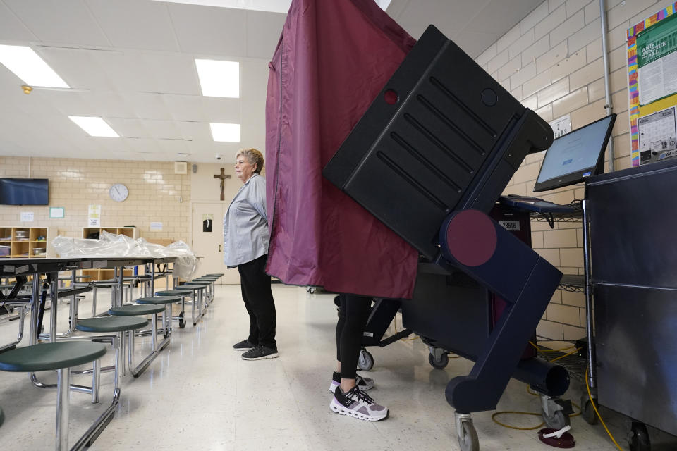 Precinct commissioner Mary Ann Winningkoff stands by as people vote at a polling place at St. Rita's Catholic School on election day in Harahan, La., Saturday, Oct. 14, 2023. (AP Photo/Gerald Herbert)
