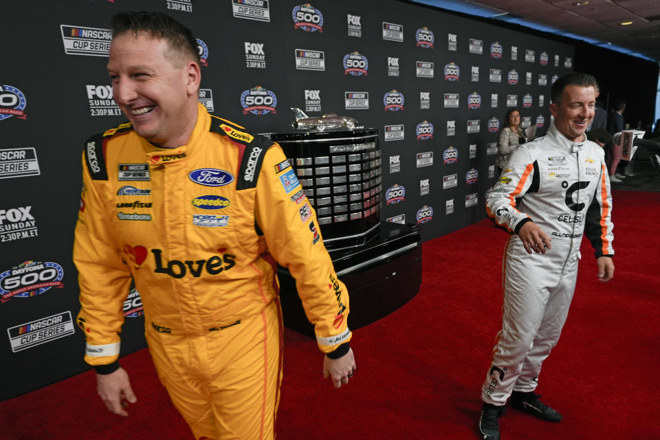 Michael McDowell, left, heads to an interview after joking around with AJ Allmendinger during NASCAR Daytona 500 auto racing media day at Daytona International Speedway, Wednesday, Feb. 14, 2024, in Daytona Beach, Fla. (AP Photo/John Raoux)