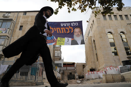 A campaign poster depicting ultra-Orthodox Jewish candidate in Jerusalem's mayoral election Yossi Daitsh is seen between buildings as an ultra-Orthodox man walks past, in Jerusalem October 18, 2018. REUTERS/Ammar Awad