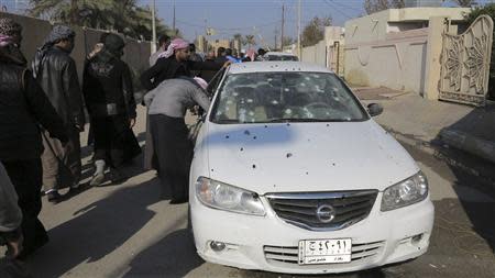 Residents inspect a bullet-riddled car outside the house of prominent Sunni Muslim lawmaker Ahmed al-Alwani in the centre of Ramadi, December 28, 2013. REUTERS/Ali al-Mashhadani