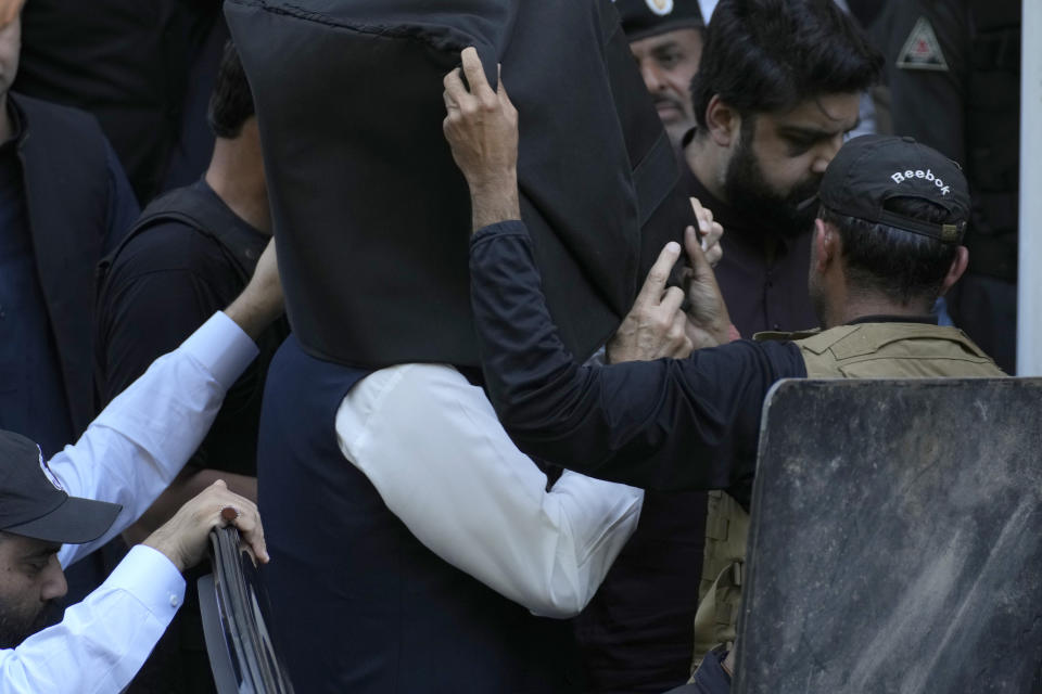 Security personnel with bulletproof shields escort former Prime Minister Imran Khan, center, as he arrives to appear in a court, in Islamabad, Pakistan, Monday, March 27, 2023. A Pakistani court ruled in defense of former Prime Minister Khan, granting him protection from arrest as lawsuits mounted against the ousted premier, with police charging him with incitement to violence in several cases when his followers clashed with the security forces this month. (AP Photo/Anjum Naveed)